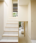 Fliesenstufen mit Holzkante auf moderner Treppe in verschachteltem, weißem Flur