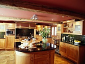 Moderne Küche aus Holz mit schwarzen Granit-Arbeitsflächen und Kochinsel in umgebauter Scheune