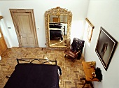 Blick von oben auf Schlafzimmer im Stilmix mit vergoldetem Spiegel auf Parkett