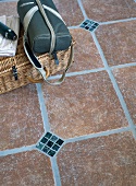 Picknickkorb auf Terracotta-Bodenfliesen mit kleinen Mosaik-Elementen
