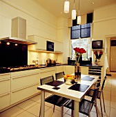 Metallstühle mit Gummibandbespannung an Esstisch mit zylindrischen Pendelleuchten in moderner, schwarzweisser Wohnküche
