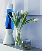 Vase mit weissen Tulpen neben einer Lava-Lampe