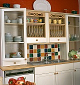 Bunte Fliesen und Tellerboard über der Edelstahl-Spüle in einer Küche