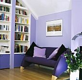 Eine Couch neben eingebautem Bücherregal in einem Wohnzimmer mit lila Wänden