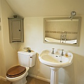 WC mit Spülkasten und ein Stand-Waschbecken in einem cremefarbenen Badezimmer