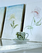 Teetasse und Untertasse mit Blumenmotiv vor floralen Bildern