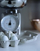 Eiern im Eierkarton vor einer Küchenwaage