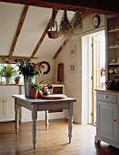 Alter, grau lackierter Holztisch mit Früchten und Blumen in Landhausküche mit Dachschräge und Holzboden