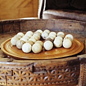 Holztablett mit gebrauchten, weissen Billardkugeln auf geschnitztem, antikem Tischchen