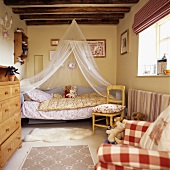 Moskitonetz über Bett mit dekorierten Teddys in Kinderzimmer mit Holzbalkendecke und rot-weiss-karierter Stoffjalousie