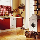Landhausküche mit weisser Waschmaschine und Geschirrspüler - in Küchenunterschränke mit roten Fronten integriert