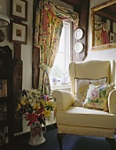 Cremefarbener Sessel und Vorhänge mit floralen Mustern im Landhaus-Wohnzimmer