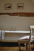 Weisser Holzstuhl und weißes freistehende Badewanne im Landhaus-Badezimmer