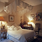 Ein romantisches Schlafzimmer mit einem Himmelbett, über das weißer Tüll angebracht wurde