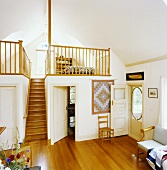 Wenig Möbel in Wohnzimmer mit Parkett, schmaler Holztreppe und Holzgeländer auf Schlafgalerie
