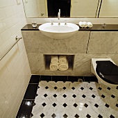 Fliesenmix in traditionellem Badezimmer mit Waschtisch mit Marmorverkleidung und Handtuchfach