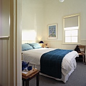 Blick in weisses Hotel-Schlafzimmer mit Kissen, Tagesdecke, Bild und Teeservice in Blautönen