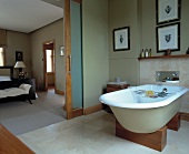 Freistehende Badewanne auf Holzelementen in Wohnbad mit grosser Schiebetür zum Schlafzimmer