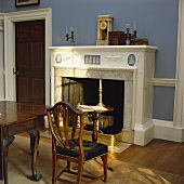 Ein Wedgewood-Kamin und antike Möbel in einem Esszimmer mit blauen Wänden
