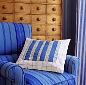 Patchwork Kissen auf einem blauen Sessel vor einer Kommode aus Kiefer