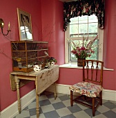 Landhauszimmer mit antikem Vogelkäfig auf einem Holztisch und antikem Stuhl mit Blumenkissen