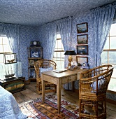 Schlafzimmer mit blau-weisser Paisley Tapete und den dazu passenden Fenster-Vorhängen, einem alten Holztisch und Bambusstühlen