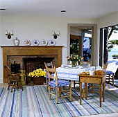 Luftiges Esszimmer mit offener Terrassentür und Meeresblick, gestreiftem Teppich und dazu passendem Tischtuch