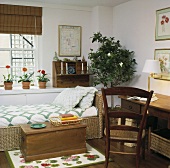 Holztruhe vor einem Rattanbett und ein Schreibtisch in einem Schlafzimmer