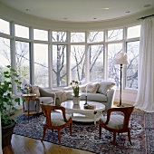 Zeitgenössisches Wohnzimmer mit halbrundem Fensterfront, grauen Sitzmöbeln und weißem Tisch