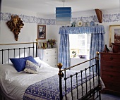 Altes Messingbett und blau-weiße Vorhänge in dem Schlafzimmer eines Landhauses