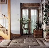 Diele mit Steinboden und Zimmerpflanzen vor einem Französischen Fenster