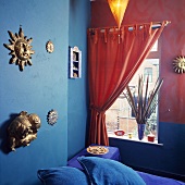 Orangefarbener Vorhang am Fenster in einem Schlafzimmer mit türkis und rosa Wänden