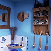 Holzregal mit Muschelsammlung in einem Bad mit blauen Wänden
