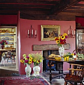 Sonnenblumen dekorieren ein rustikales Esszimmer mit Holzbalkendecke und roten Wänden