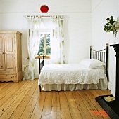Grosses weisses Schlafzimmer mit Holzdielen und einem Bett mit weisser Bettwäsche