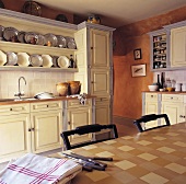 Tischdecke mit Karomuster in heller Landhausküche mit Zinktellern im Board über Küchenzeile