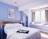 Frühstückstablett auf dem Bett im ländlichen Schlafzimmer mit violett getönten Wänden