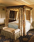 Antikes Himmelbett mit floralen Vorhängen in einem ländlichen Schlafzimmer