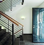 Eingangsbereich mit Treppe, grauen Bodenfliesen und blauer Tür