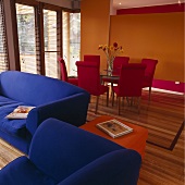 Rote Esszimmerstühle und blaue Sofagarnitur in einem offenen Wohn- und Esszimmer