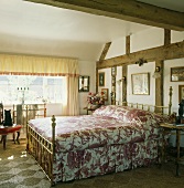 Doppelbett mit Messinggestell im rustikalen Schlafzimmer mit alter Holzkonstruktion in Wand