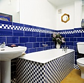 Badewanne in weiss blauem Schachbrettmuster gefliest vor Wand mit blauen Fliesen