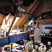 Alte Küche unter Dach mit blau bemalten Unterschränken und altem Küchenofen