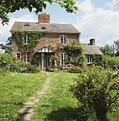 Altes englisches Landhaus in Ziegelbauweise mit Weg durch Garten