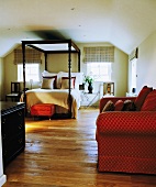 Rotes glänzendes Sofa in weißem Schlafzimmer im Dachgeschoss mit antikem Himmelbett