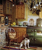 Alte Landhausküche mit Ziegelwand und Hund neben Stuhl