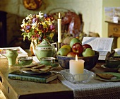 Teepause mit Keksen neben brennenden Kerzen und Obstschale auf dem Tisch