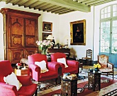 Rote Polstersessel und orientalische Beistelltische vor antikem Schrank im traditionellen Mediterraner Wohnzimmer