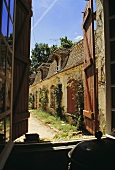 Blick aus offenem Fenster mit Fensterläden auf altes französisches Landhaus