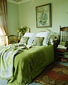 Grüne Tagesddecke mit auf Doppelbett in lindgrünem Schlafzimmer